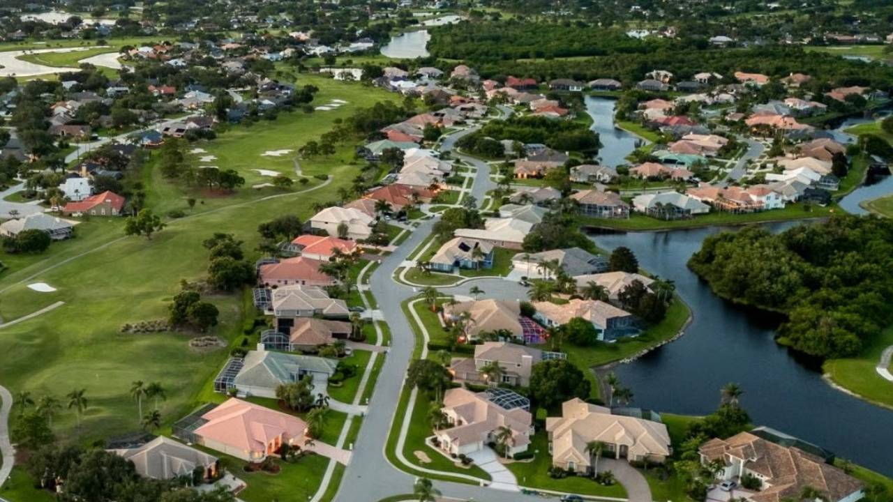 Aerial view of a suburban neighborhood with winding streets, lakes, and a green golf course nearby.