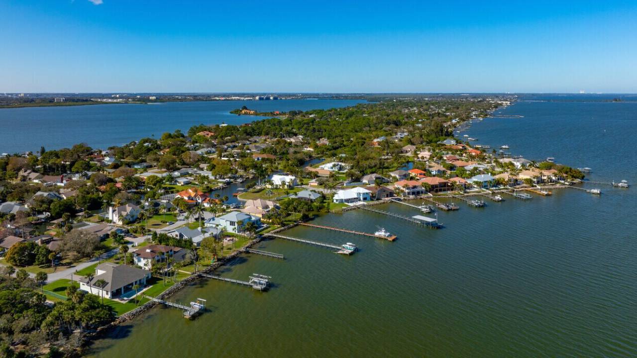 Aerial view of a coastal neighborhood with houses along a canal and private docks.